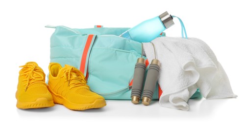 Photo of Stylish sports bag with skipping rope, towel, bottle and sneakers isolated on white