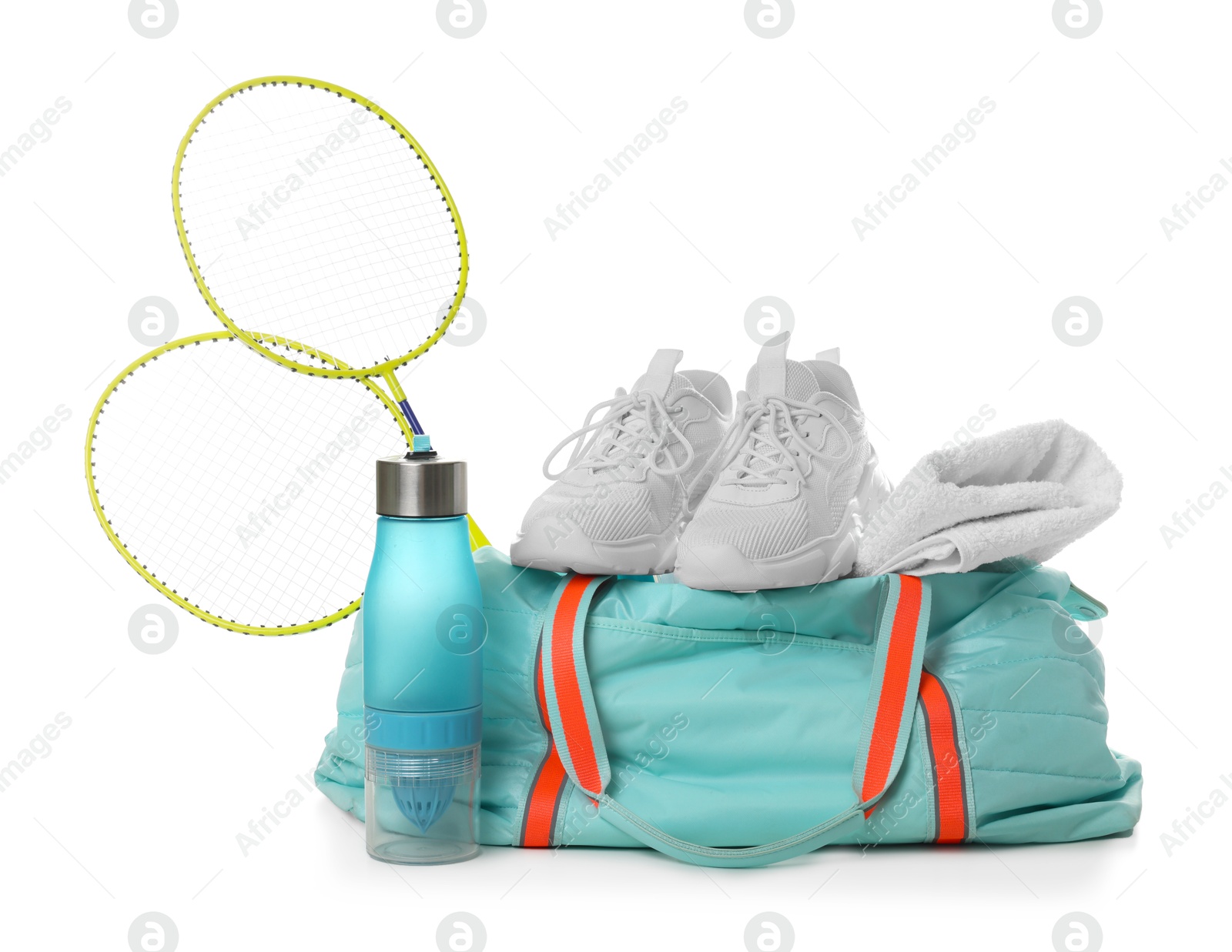 Photo of Stylish sports bag with badminton rackets, towel, bottle and sneakers isolated on white