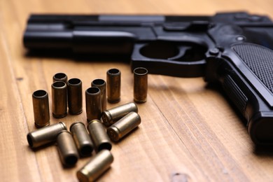 Photo of Bullets and gun on wooden table, closeup