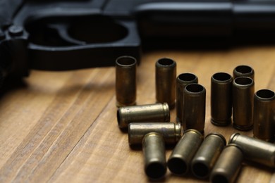 Photo of Bullets and gun on wooden table, closeup