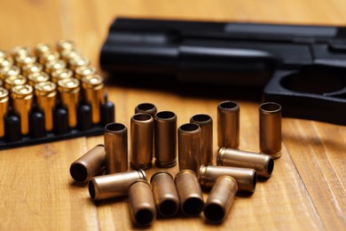 Photo of Bullets and gun on wooden table, closeup