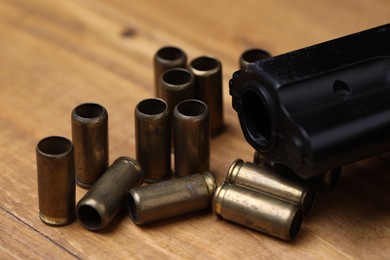 Photo of Bullets and gun on wooden table, closeup