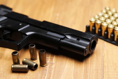 Photo of Bullets and gun on wooden table, closeup