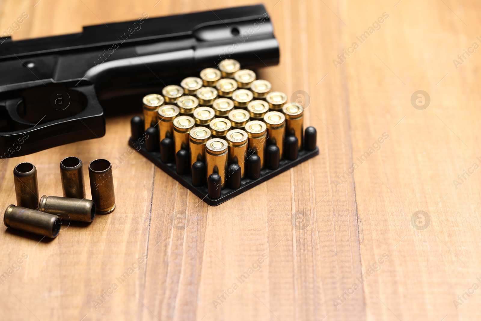 Bullets and gun on wooden table, closeup. Space for text Photo of Bullets and gun on wooden table, closeup. Space for text