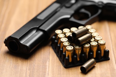 Photo of Bullets and gun on wooden table, closeup