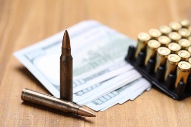 Photo of Bullets and dollars on wooden table, closeup