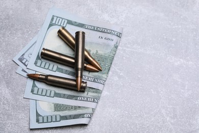 Photo of Bullets and dollars on grey table, flat lay. Space for text