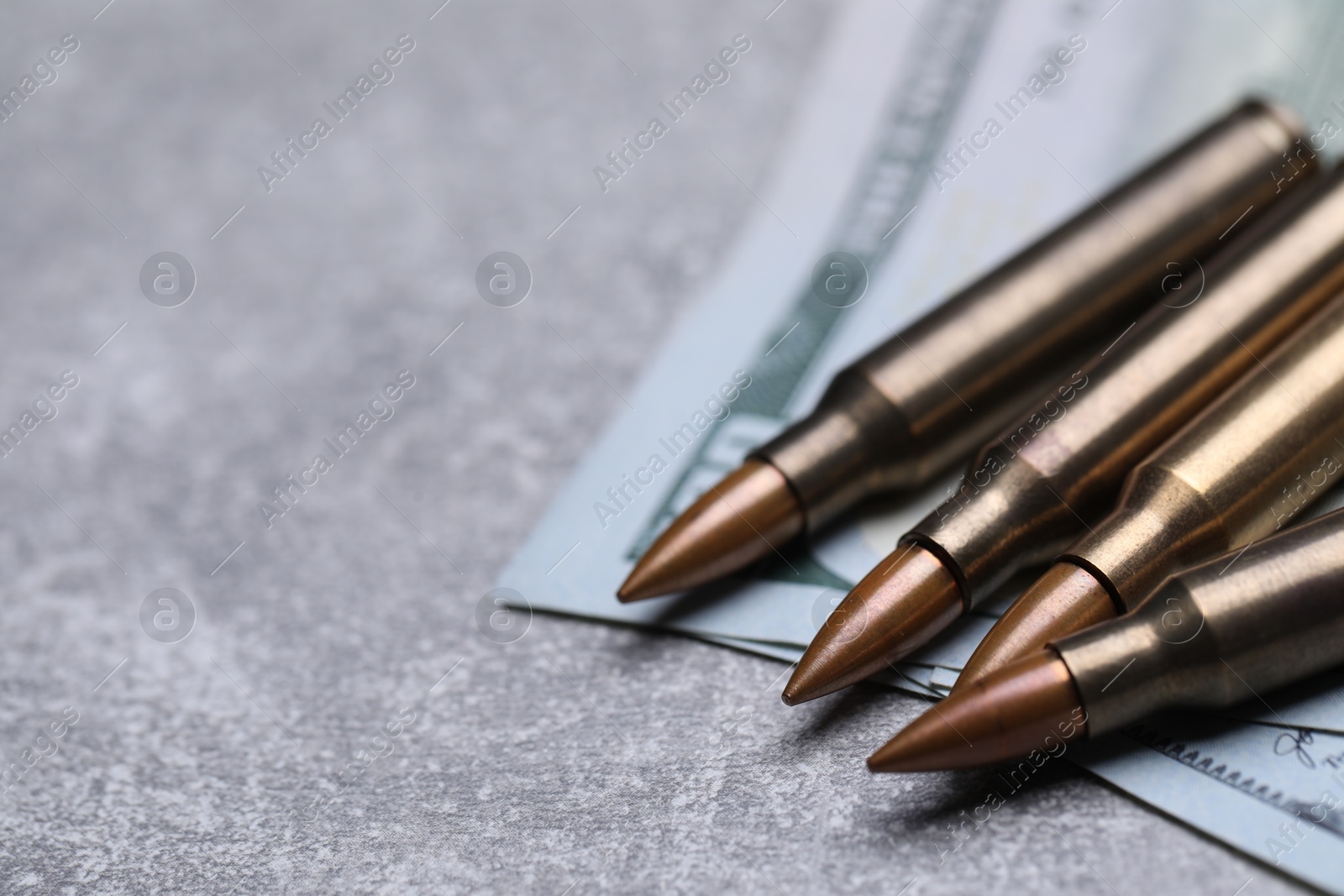 Bullets and dollars on grey table, closeup. Space for text Photo of Bullets and dollars on grey table, closeup. Space for text