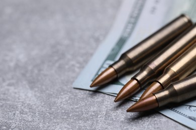 Photo of Bullets and dollars on grey table, closeup. Space for text