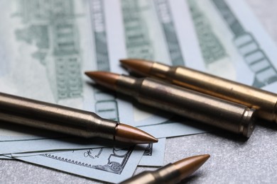 Photo of Bullets and dollars on grey table, closeup