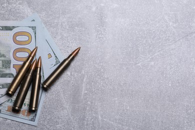 Photo of Bullets and dollars on grey table, flat lay. Space for text
