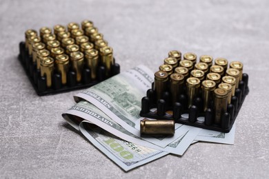 Photo of Bullets and dollars on grey table, closeup