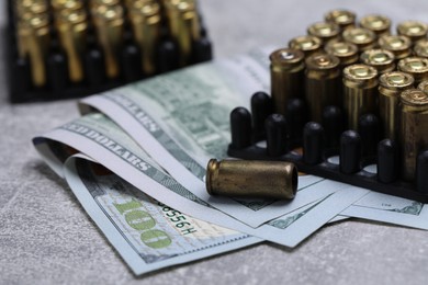 Photo of Bullets and dollars on grey table, closeup