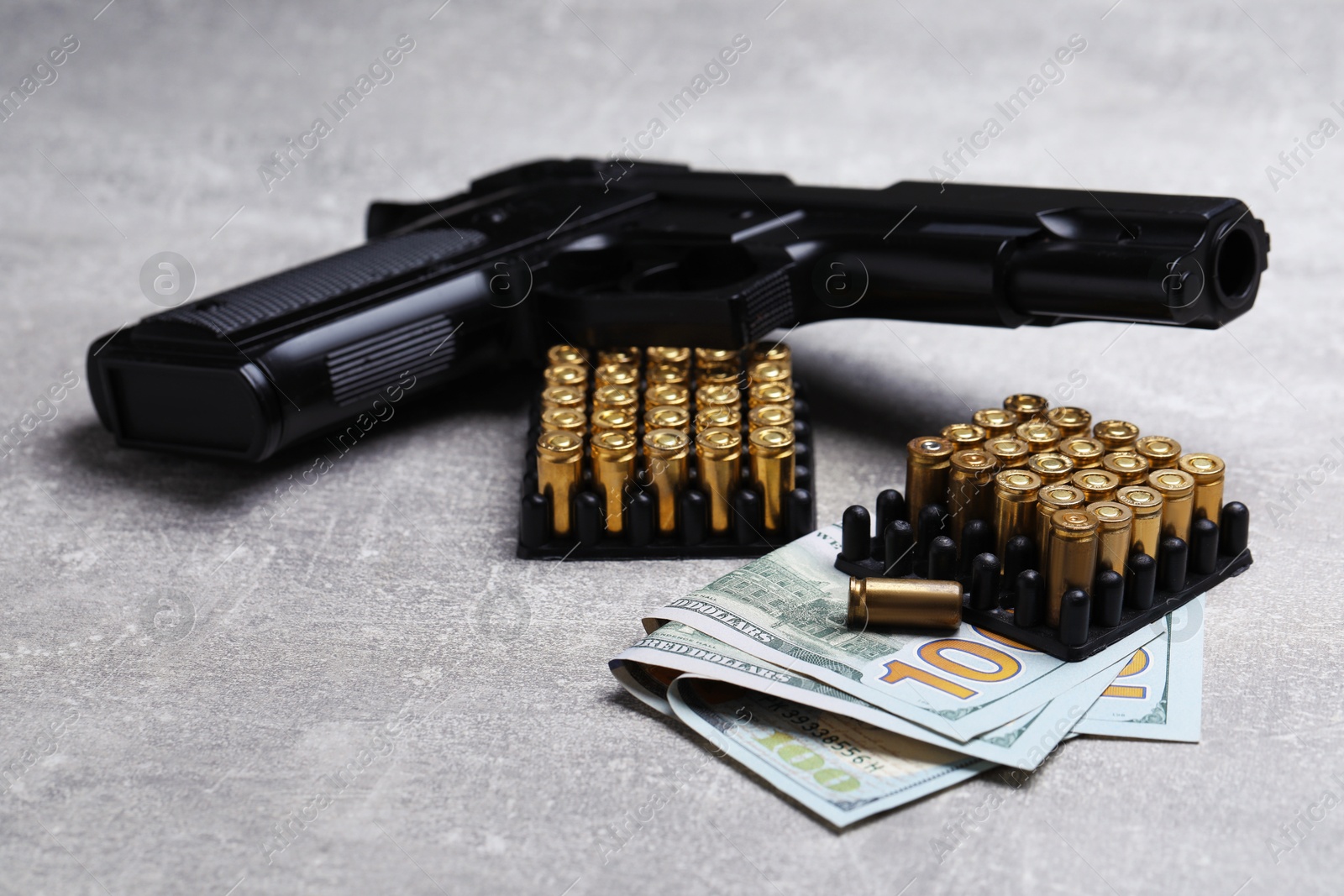 Bullets, gun and dollars on grey table, closeup Photo of Bullets, gun and dollars on grey table, closeup