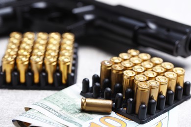 Photo of Bullets, gun and dollars on grey table, closeup