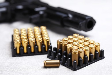Photo of Bullets and gun on grey table, closeup