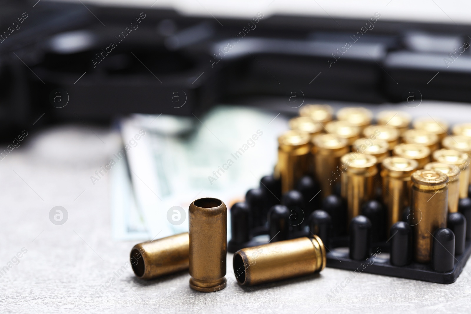 Bullets, gun and dollars on grey table, closeup Photo of Bullets, gun and dollars on grey table, closeup