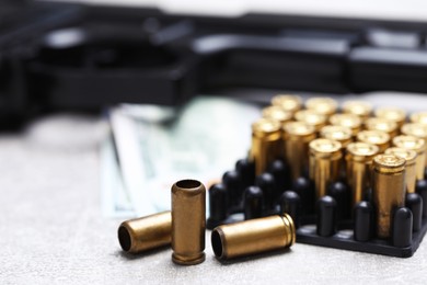 Photo of Bullets, gun and dollars on grey table, closeup