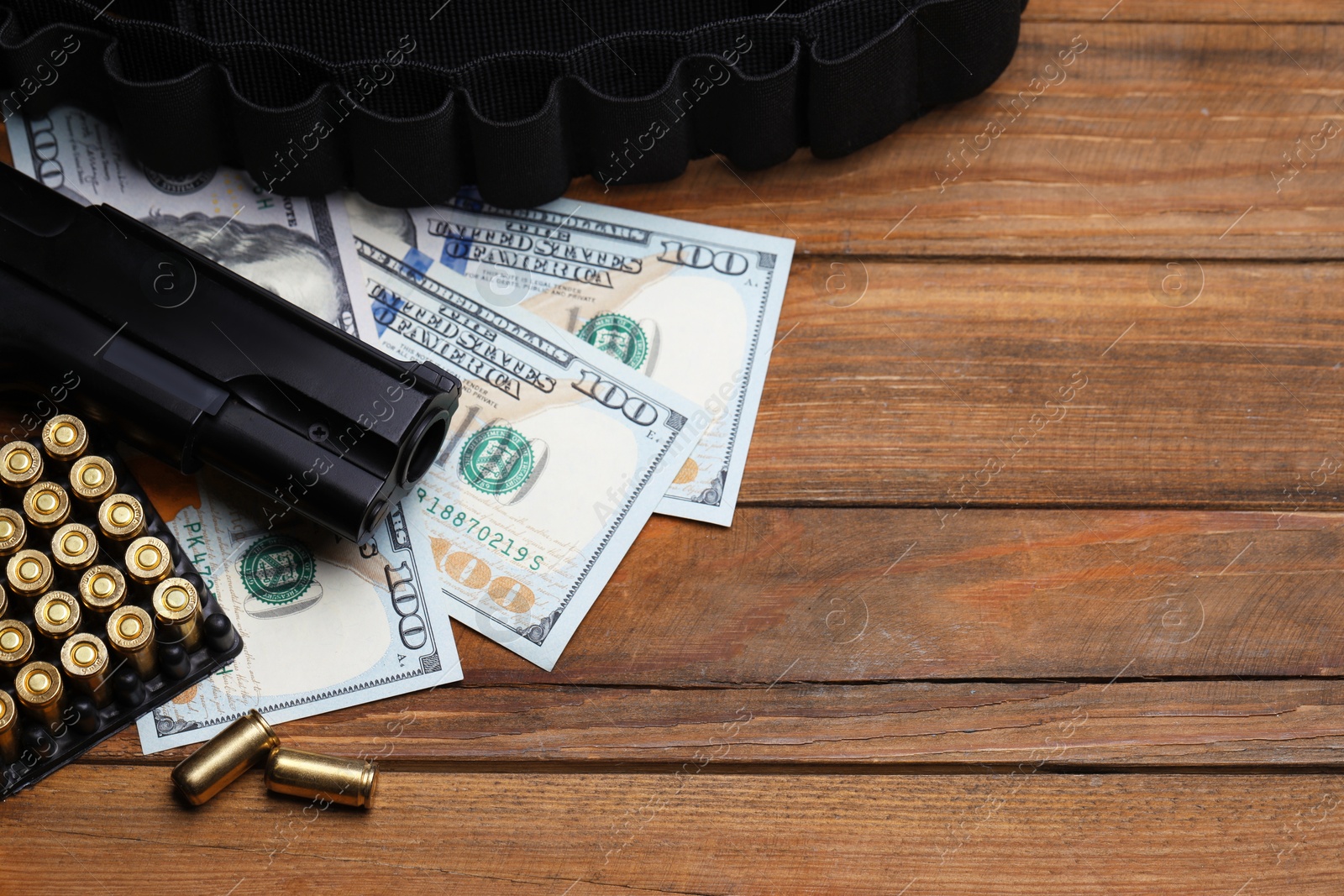 Bullets, gun, dollars and ammunition belt on wooden table, flat lay. Space for text Photo of Bullets, gun, dollars and ammunition belt on wooden table, flat lay. Space for text