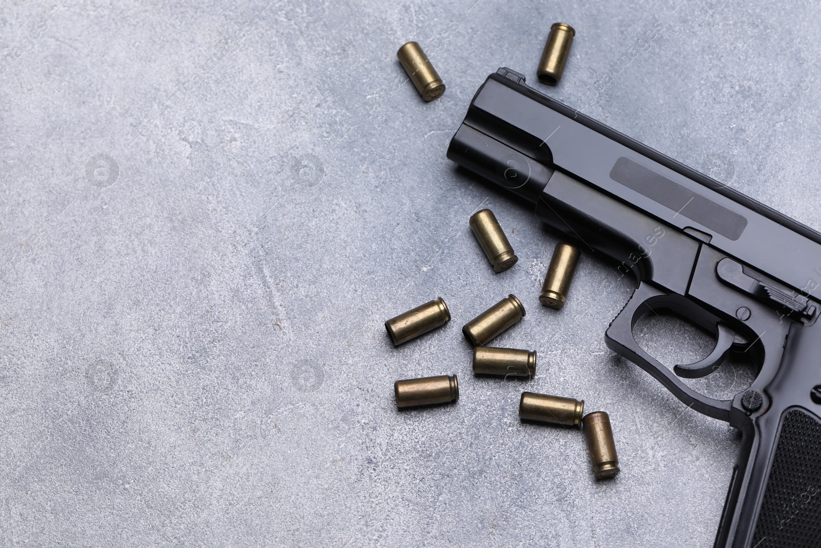 Bullets and gun on grey table, flat lay. Space for text Photo of Bullets and gun on grey table, flat lay. Space for text