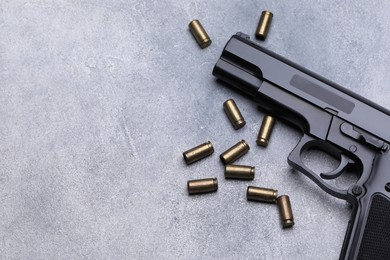 Photo of Bullets and gun on grey table, flat lay. Space for text