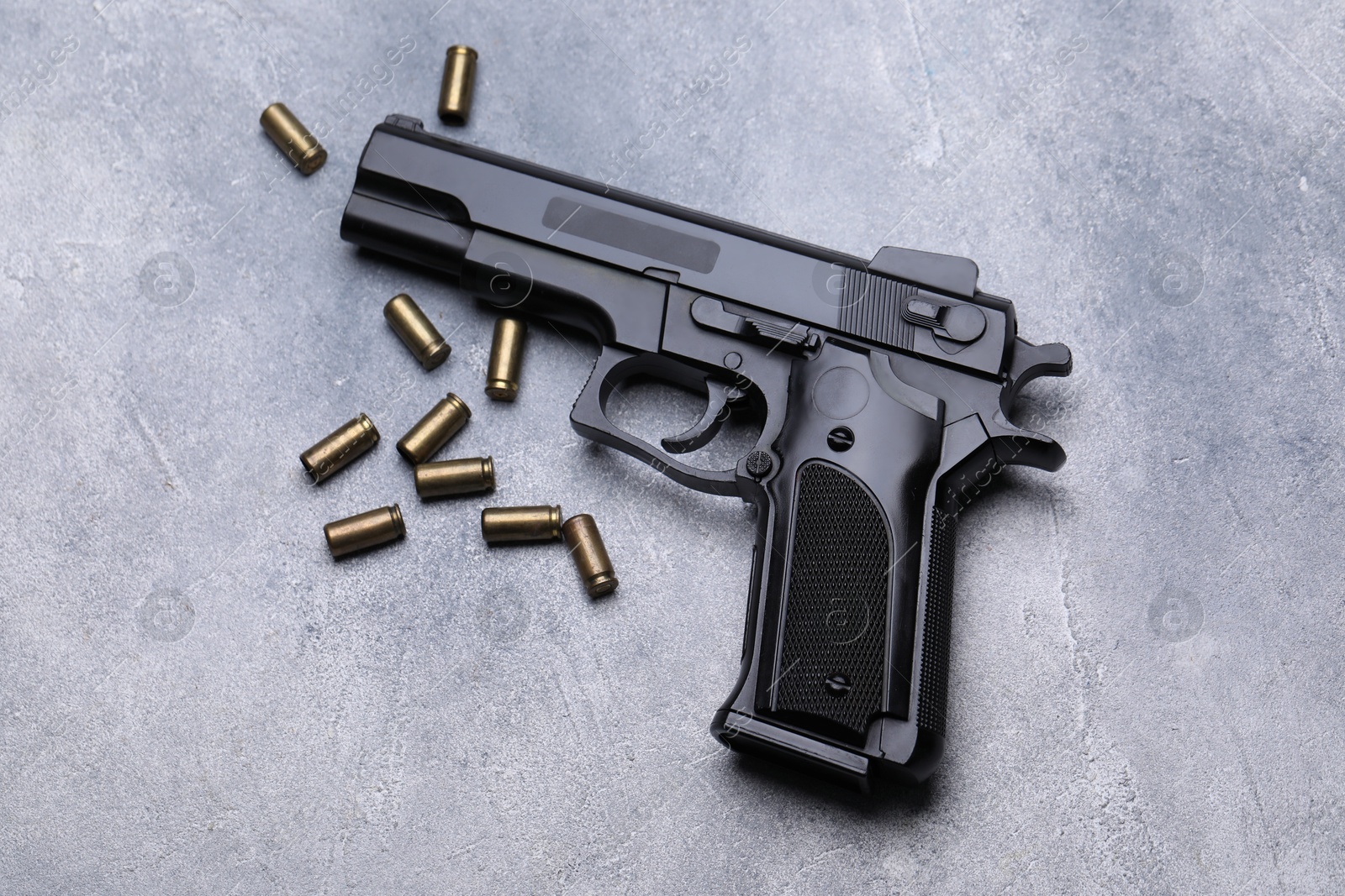 Bullets and gun on grey table, flat lay Photo of Bullets and gun on grey table, flat lay