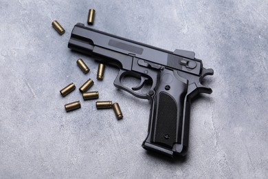Photo of Bullets and gun on grey table, flat lay