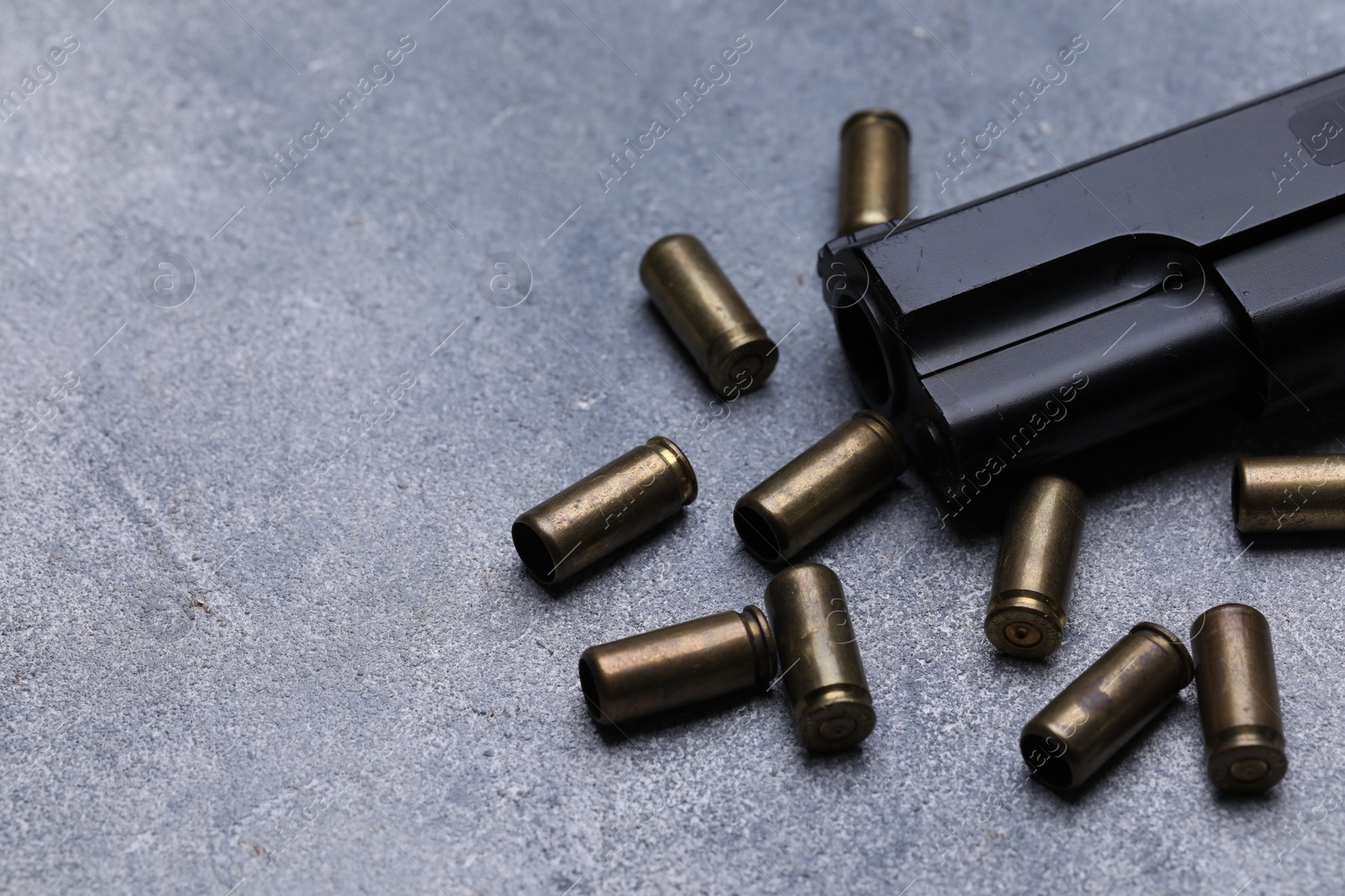 Bullets and gun on grey table, closeup. Space for text Photo of Bullets and gun on grey table, closeup. Space for text
