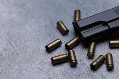 Photo of Bullets and gun on grey table, closeup. Space for text