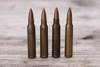 Photo of Many metal bullets on wooden table, closeup