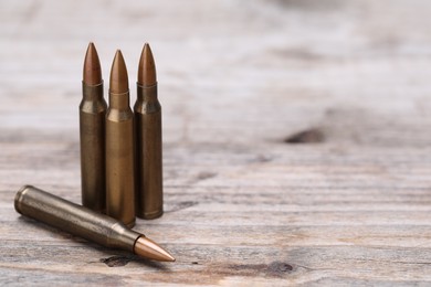 Photo of Many metal bullets on wooden table, closeup. Space for text