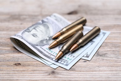 Photo of Bullets and dollars on wooden table, closeup