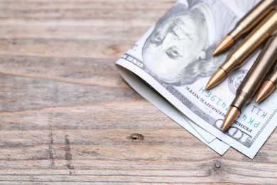 Photo of Bullets and dollars on wooden table, above view. Space for text