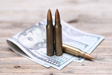 Photo of Bullets and dollars on wooden table, closeup