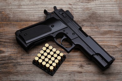 Photo of Metal bullets and gun on wooden table, flat lay
