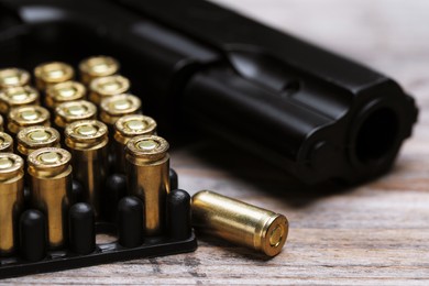 Photo of Metal bullets and gun on wooden table, closeup