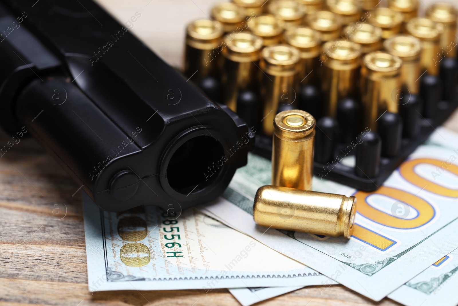 Metal bullets, gun and dollars on wooden table, closeup Photo of Metal bullets, gun and dollars on wooden table, closeup