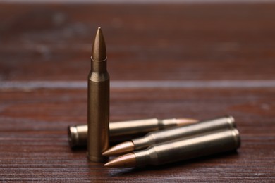 Photo of Many metal bullets on wooden table, closeup