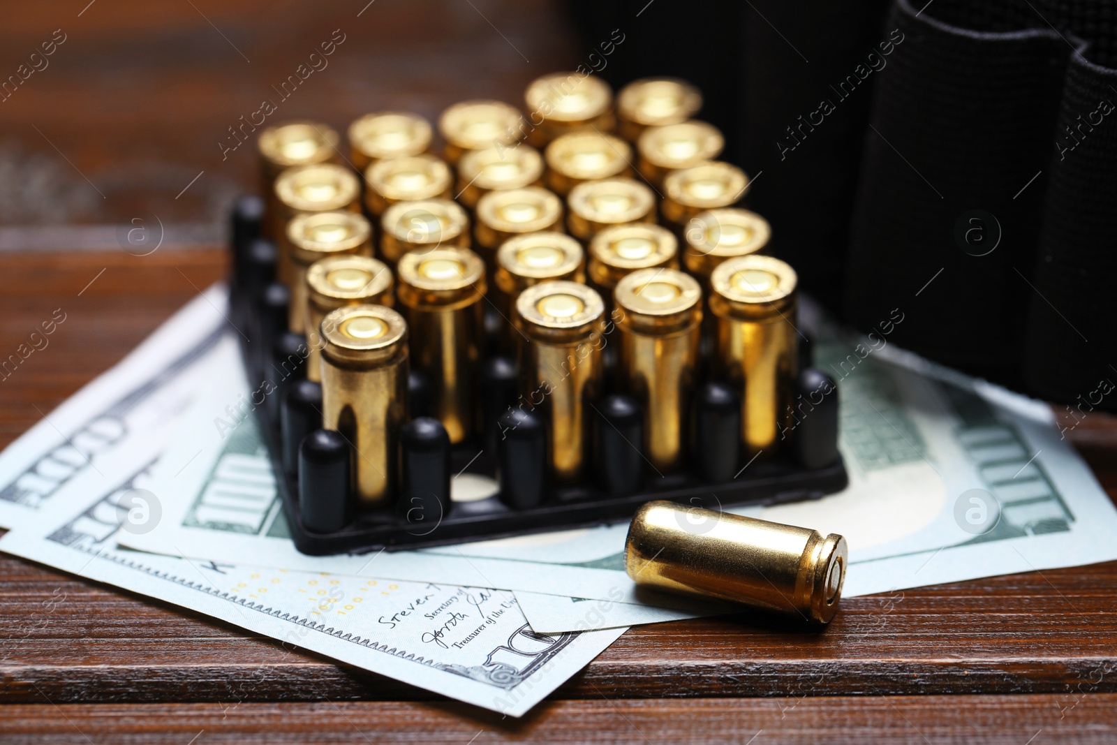 Many metal bullets, dollars and ammunition belt on wooden table, closeup Photo of Many metal bullets, dollars and ammunition belt on wooden table, closeup
