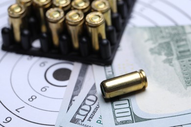 Photo of Many metal bullets and dollars on shooting target, closeup