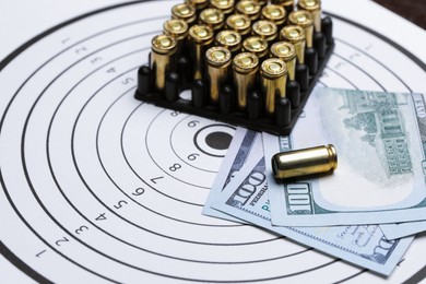 Photo of Many metal bullets and dollars on shooting target, closeup