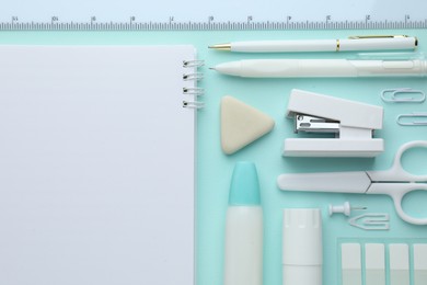 Photo of White notepad and other stationery on turquoise background, flat lay. Space for text