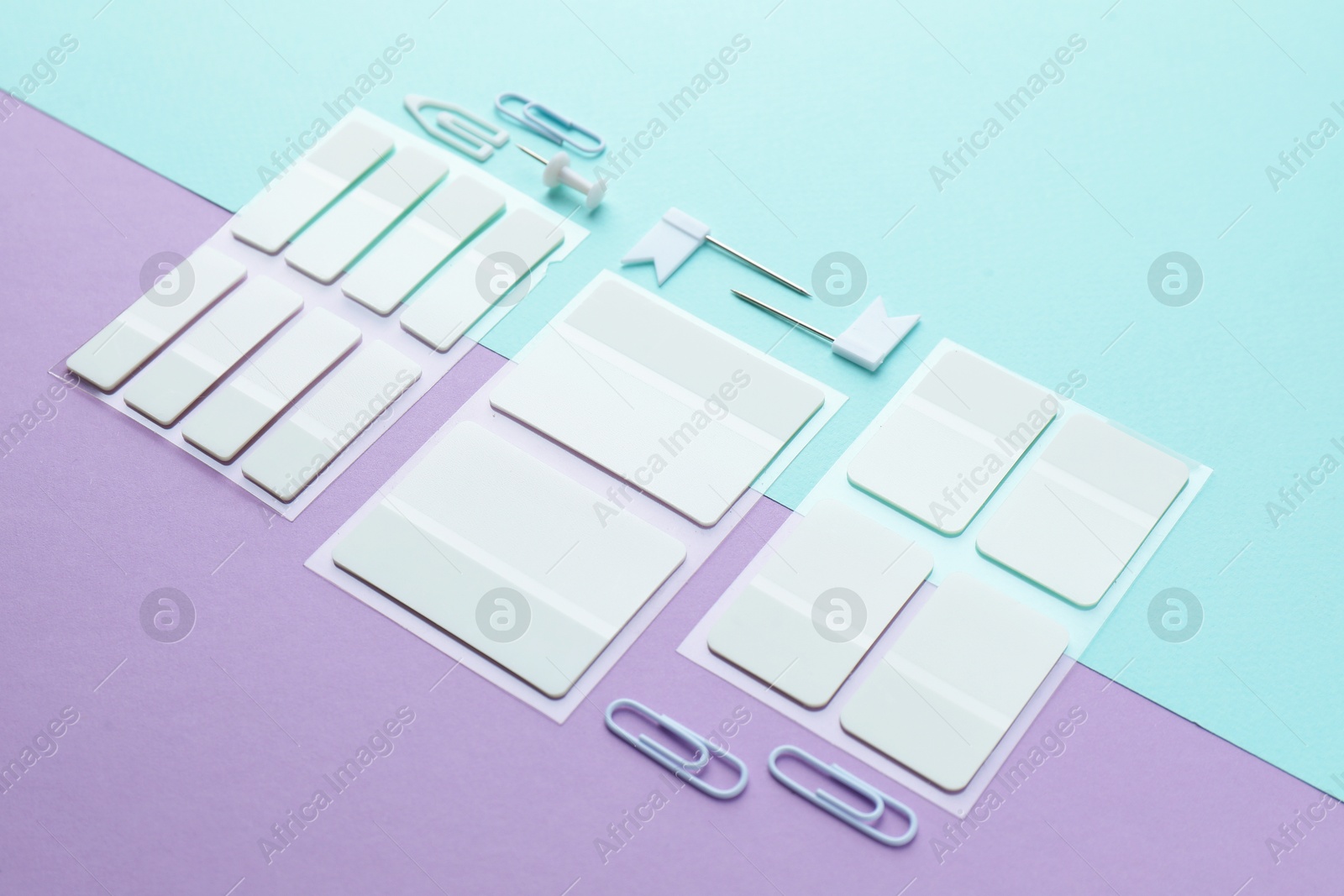 White sticky tabs and other stationery on color background, closeup Photo of White sticky tabs and other stationery on color background, closeup