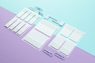 Photo of White sticky tabs and other stationery on color background, closeup