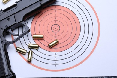 Photo of Many metal bullets and gun on shooting target, flat lay