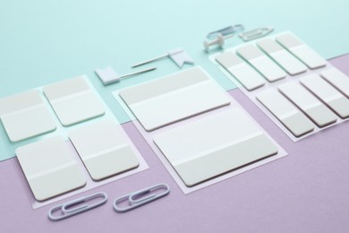 Photo of White sticky tabs and other stationery on color background, closeup