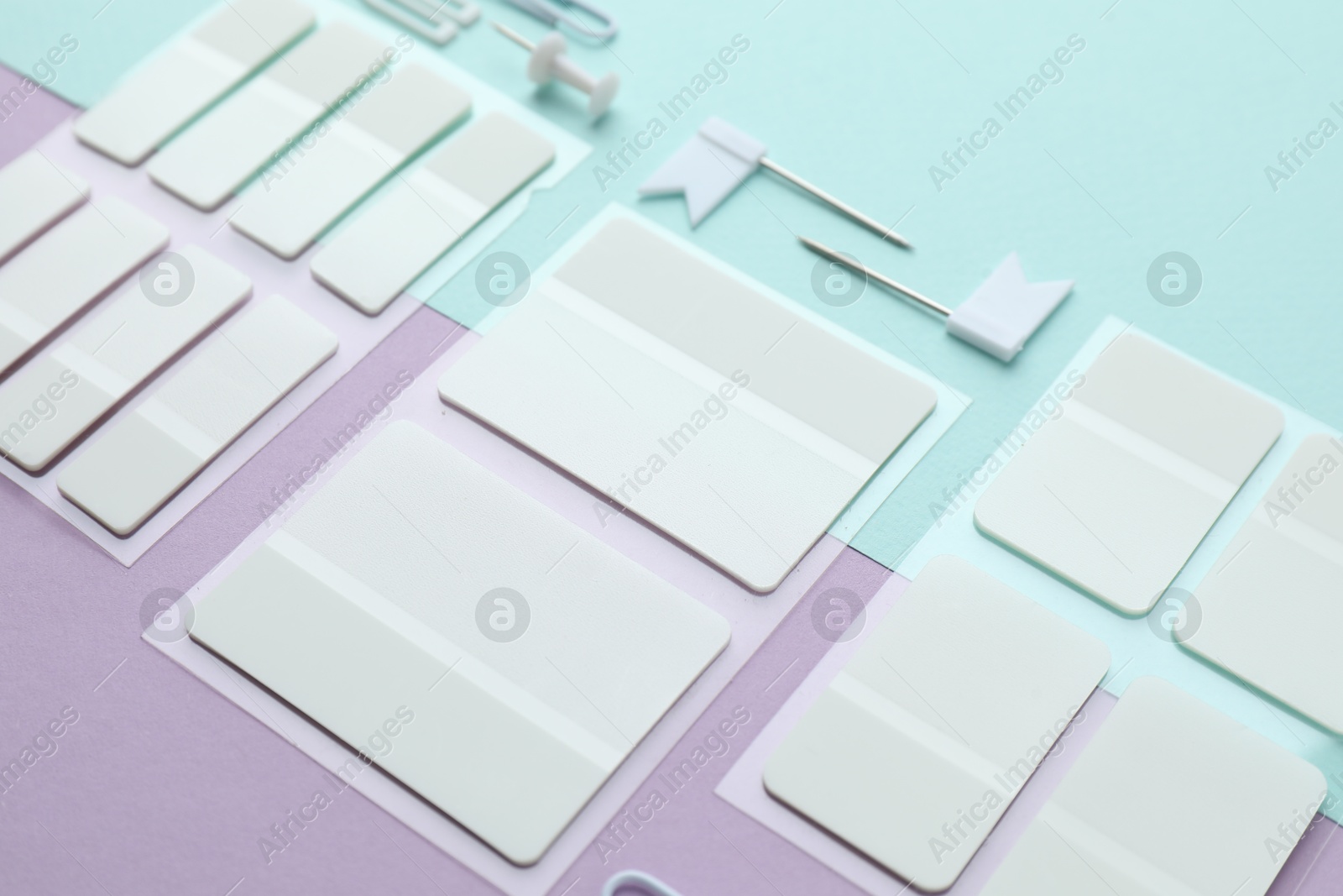 White sticky tabs and other stationery on color background, closeup Photo of White sticky tabs and other stationery on color background, closeup