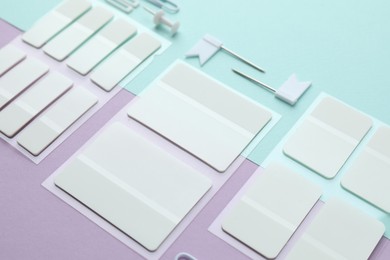 Photo of White sticky tabs and other stationery on color background, closeup