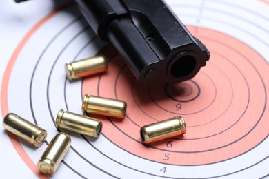 Photo of Many metal bullets and gun on shooting target, closeup