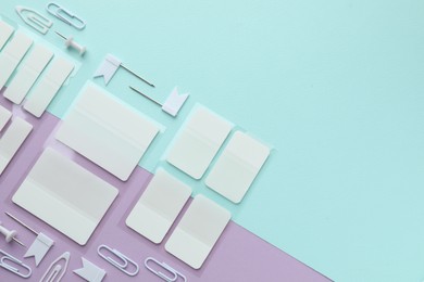 Photo of White sticky tabs and other stationery on color background, flat lay. Space for text